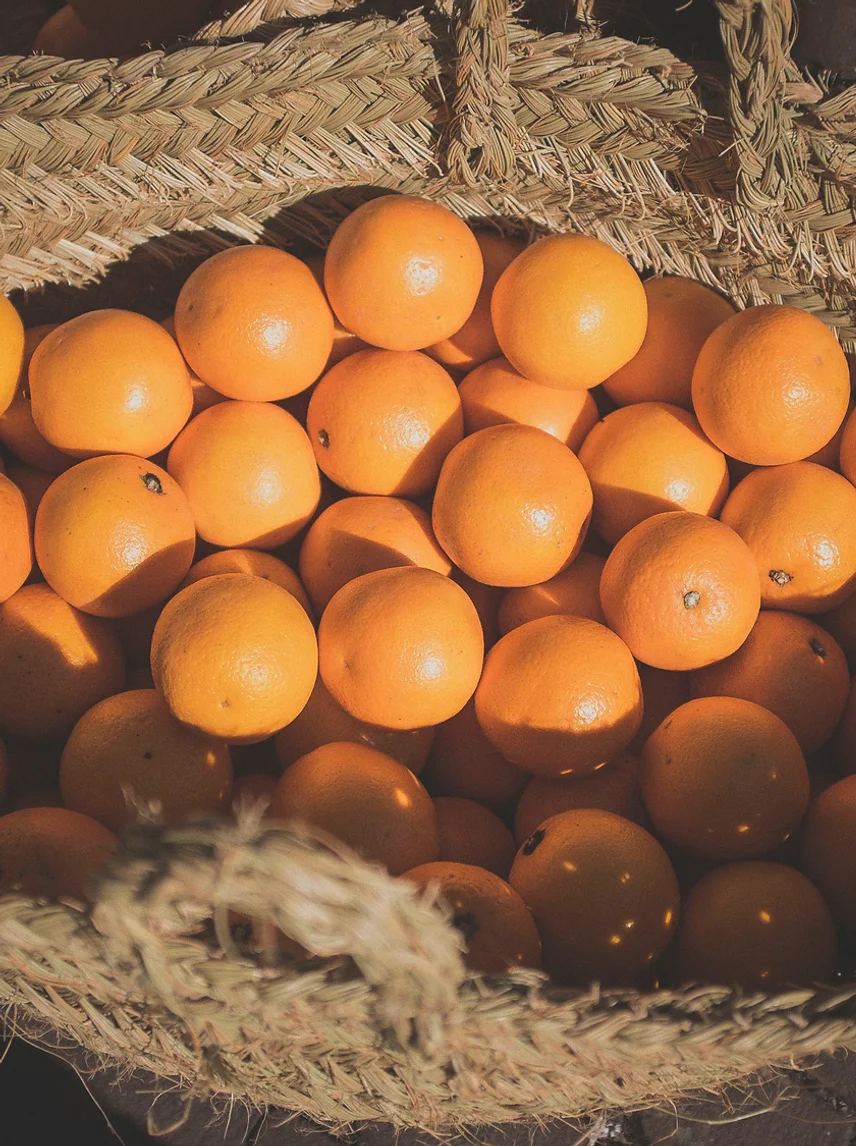 Oranges fraîches dans un panier en osier pour le parfum d'enfance - Notes de fleur d'oranger méditerranéenne